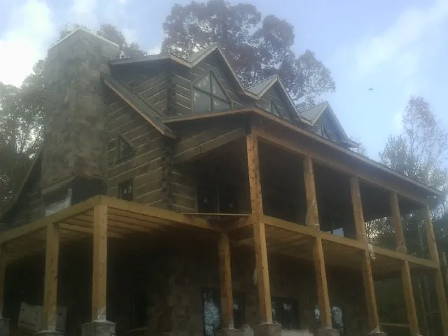 Stone chimney and dormers on a large log home with a timber porch in La Porte